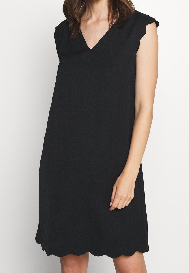 Robe noire sans manches avec un ourlet festonné et un décolleté en V. Fabriquée en tissu doux, elle présente une coupe droite et un design minimaliste.