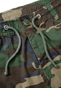 Pantalones cortos camuflados con un cordón y cierre de botón en ojal verde. Fabricados con una tela con texturas en diversos tonos de verde y marrón.