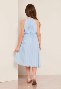 Vaaleansininen, laskostettu mekko, jossa on halterneck-olkaimet, vyötäröä korostava malli ja polveen ulottuva hame. Selässä on nappikiinnitys ja hienovarainen kiilto.