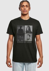 Sort bomulds-t-shirt med fire monokrome portrætter i et gitterlayout, med teksten "KINGS OF LEON" i fed skrift under billederne.