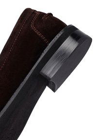 Talons de chaussure en daim marron foncé avec semelle en bois noire empilée et couture visible sur la partie supérieure.