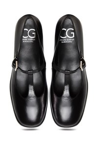 Mustat nahkakengät, joissa on T-hihnallinen muotoilu, pyöreä kärki, kiiltävä pinta ja hopeanväriset solkiyksityiskohdat. Merkattu "CG Cesare Gaspari Barcelona".