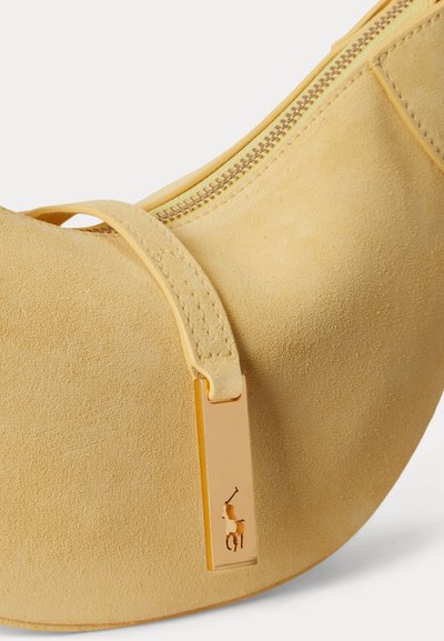 Κίτρινη τσάντα χειρός σε σχήμα ημισελήνου από σουέντ με χρυστό φερμουάρ και χρυσό κρεμαστό διακοσμητικό με λογότυπο παίκτη πόλο στην λαβή του φερμουάρ.