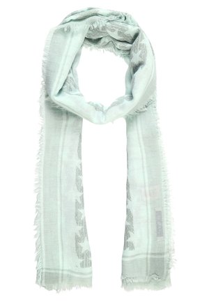 Écharpe vert clair aux bords effilochés, avec un motif étoilé subtil et des bordures rayées tissées, bouclée lâchement avec les extrémités pendantes.