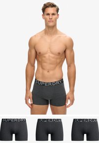 Boxer-briefs pour hommes en gris foncé avec une taille noire portant l'inscription "SUPERDRY" dans une police contrastante. Le tissu semble doux et extensible.