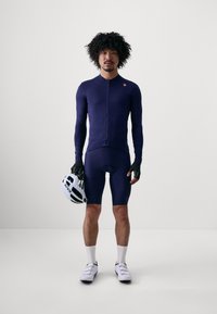 Marinefarbener Radtrikot- und Shorts-Satz, langärmlig, mit vollem Reißverschluss, dazu Handschuhe und ein weißer Helm. Bietet eine enganliegende Passform und glatte Textur.