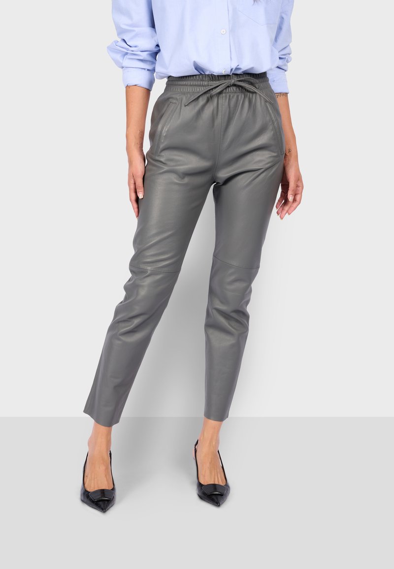 Šedé kožené kalhoty se zúženým střihem, elastickým pasem a šňůrkou. V kombinaci s černými lodičkami s špičatou špičkou.