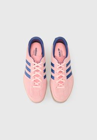 Roza semišna športna obutev z mornarskimi črtami, zavezujoč dizajn, podložen ovratnik in gumijast podplat. Ima blagovno znamko na notranji strani in logo na jeziku.