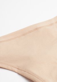 Nude-färgad tyg bikiniunderdel med en slät textur, med en sömlös midja och rena sömmar längs kanterna.
