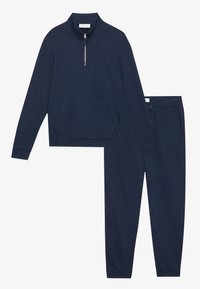 Marinblå zip-up sweatshirt med en framficka och matchande avsmalnande sweatpants med justerbart snöre i midjan. Mjuk tygtextur.