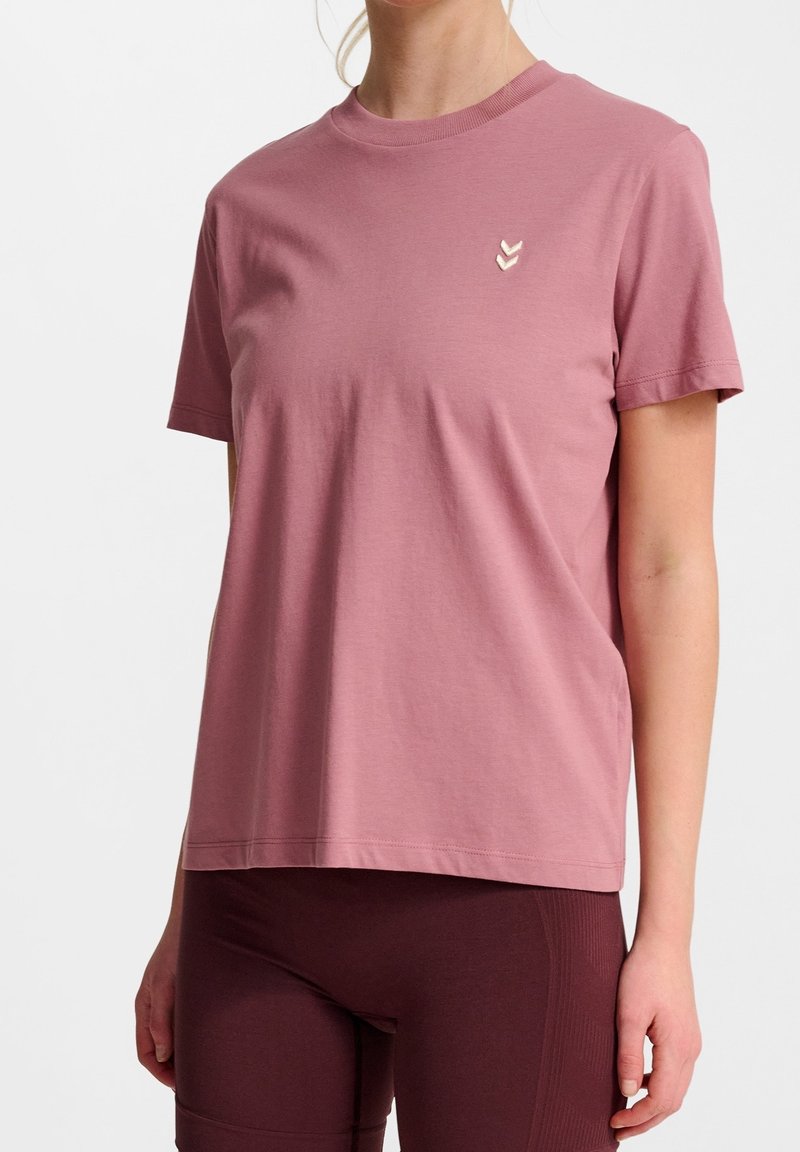 Kurzarm-T-Shirt mit rundem Halsausschnitt aus staubrosa Baumwolle, ausgestattet mit einem kleinen, hellroza Chevron-Logo auf der linken Brust. Klassische, lockere Passform.