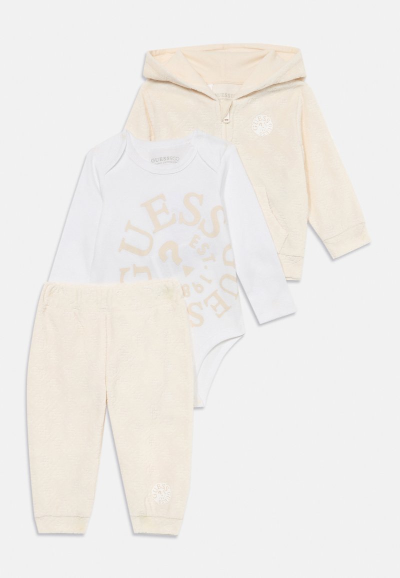 Trzyczęściowy zestaw dla malucha: miękka kremowa bluza z zamkiem, biała body z beżowym napisem oraz teksturowane kremowe spodnie z detalem logo.