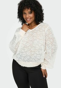 Bijela čipkasta bluzica s dugim, napučenim rukavima i rebrastim manžetama. Tkanina je lagana i prozirna, stvarajući delikatan izgled.