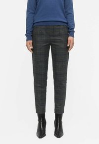 Plaid trousers in dark gray with a tailored fit, featuring a fine check pattern and slim legs. Paired with black, pointed-toe ankle boots.