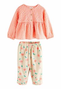 Blusa button-up a quadretti corallo chiaro con maniche a palloncino, abbinata a pantaloni crema con motivi floreali rosa e teal. Materiale in cotone morbido.