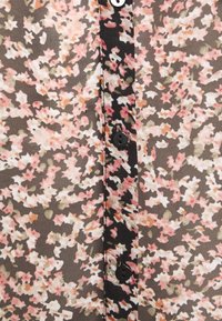 Bluse mit Blumenmuster aus transparentem Stoff, ausgestattet mit einer schwarzen Knopfleiste. Die Farben umfassen Rosa, Beige und olivgrün auf einem dunklen Hintergrund mit einem gemischten Muster.