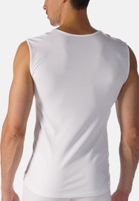 White sleeveless tank top made of smooth, stretchy fabric. Features a rounded neckline, fitted silhouette, and subtle side seams.