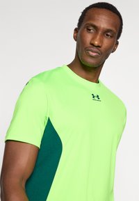 Φωτεινό πράσινο αθλητικό μπλουζάκι με κοντά μανίκια και σκοτεινό πράσινο πλαϊνό πάνελ. Διαθέτει στρογγυλή λαιμόκοψη και ένα μικρό λογότυπο στο στήθος.