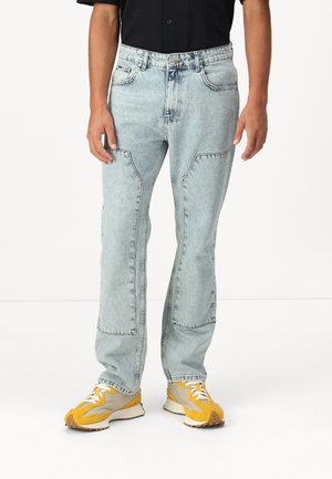 Hellblaue Denim-Jeans mit lockerem Schnitt, ausgestattet mit aufgesetzten Taschen, sichtbaren Nähten und geradem Bein.