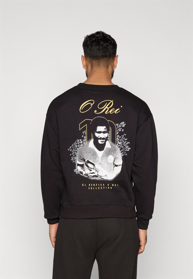 Felpa nera con scollo rotondo, decorata con una grafica di un calciatore e la scritta "O Rei 10" in oro. Maniche e bordo inferiori a costine.