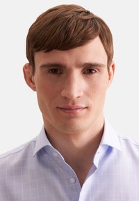 Jasnoniebieska koszula z guzikami, w kratę, z klasycznym kołnierzykiem i subtelną fakturą. Materiał wygląda na gładki i dopasowany.