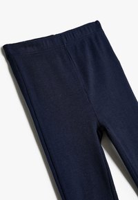 Granatowe legginsy prążkowane z elastycznym paskiem w talii, charakteryzujące się gładką fakturą i dopasowanym krojem, zaprojektowane z myślą o komforcie i wszechstronności.