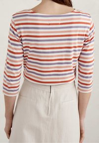 Randig topp i mjuk bomullsblandning, med horisontella band i korall, lavendel och vitt. Trekvartsärmar och en avslappnad passform.
