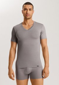 T-shirt grigio a maniche corte con scollatura a V in un tessuto elasticizzato, abbinato a boxer aderenti. Il design è aderente, con una texture liscia e un branding minimale.