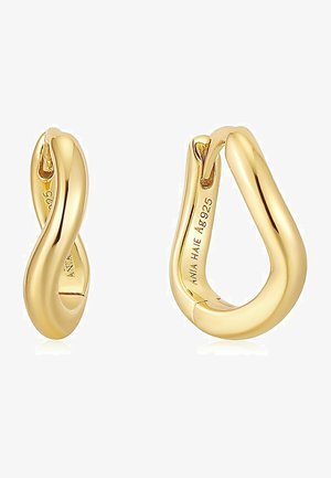 Boucles d'oreilles en or en forme de créole avec un design torsadé, présentant des surfaces lisses et brillantes ainsi qu'une fermeture sécurisée. Marquées avec des détails de marque et de matériau à l'intérieur.