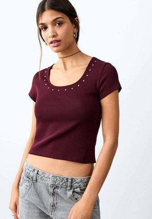 Top burgundy mulat, cu mâneci scurte și decolteu rotund, decorat cu nituri argintii de-a lungul decolteului. Material moale și elastic.