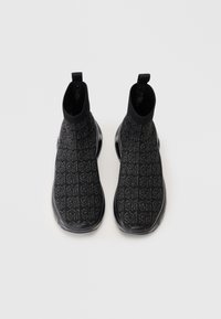 Para czarnych sneakersów typu high-top na skarpetkach z wzorzystą dzianiną u góry i uchwytami na białym tle.