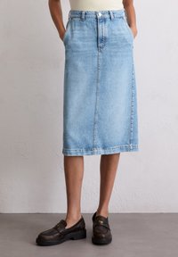 Lichtblauwe denim midi-rok met een rechte snit, vijf riemlussen, voorzakken en een knoopsluiting aan de voorkant. Gestructureerde stof met een vervaagde uitstraling.