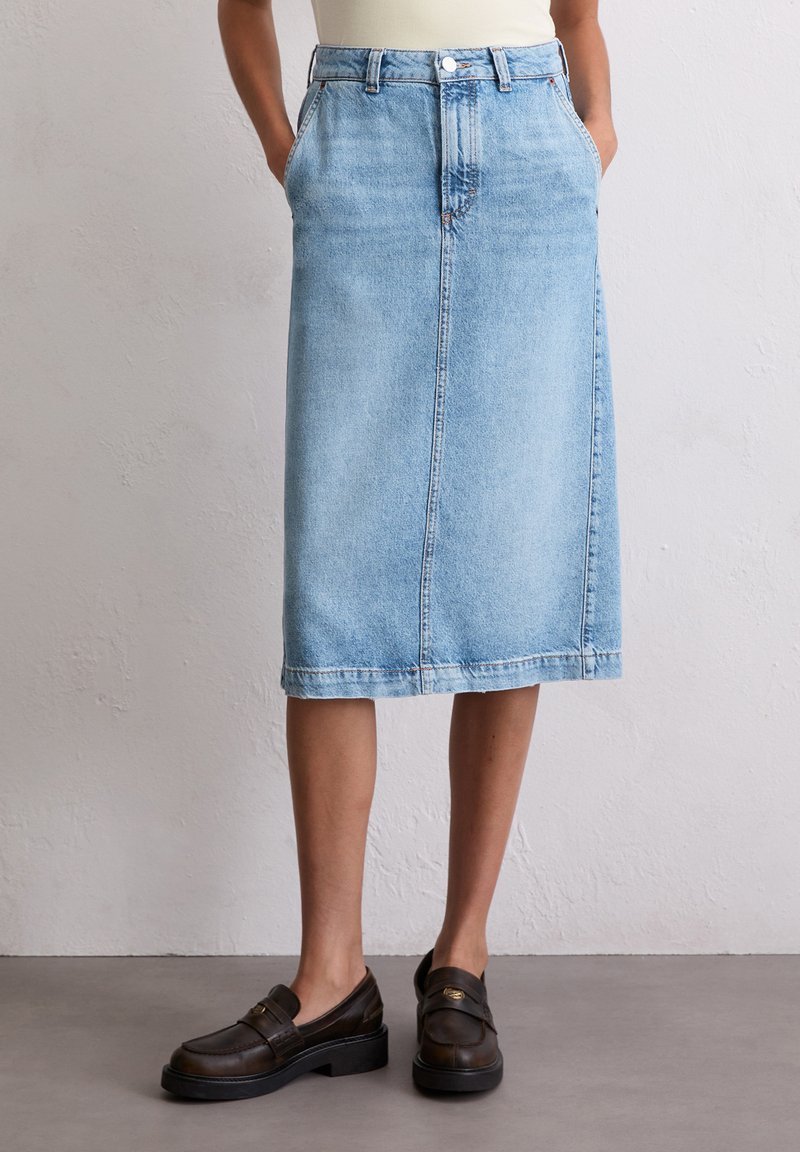 Lichtblauwe denim midi-rok met een rechte snit, vijf riemlussen, voorzakken en een knoopsluiting aan de voorkant. Gestructureerde stof met een vervaagde uitstraling.