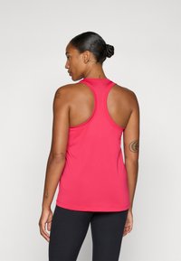 Canotta atletica fucsia aderente con design a schiena scoperta, realizzata in tessuto leggero e morbido. Dotata di cuciture minime per garantire comfort.
