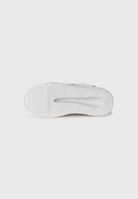 Suola di sneaker bianca con modelli di presa in gomma testurizzata, forma curvata e dettaglio del marchio impresso vicino al tallone. Progettata per aderenza e comfort.