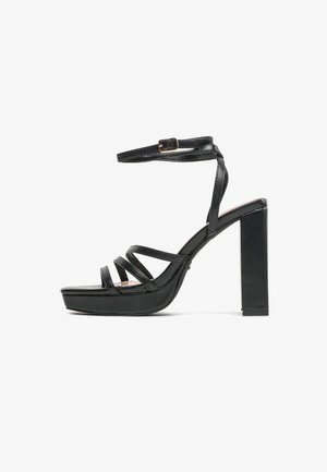 Czarna sandałka na wysokim obcasie z platformą, paskiem wokół kostki oraz wieloma cienkimi paskami na palcach, widok z boku na białym tle.