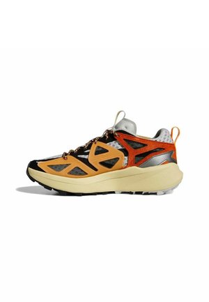 Trail hardloopschoen met beige zool, oranje en zwarte mesh bovenwerk, reflecterende grijze accenten en trekriempjes op de tong en hiel.