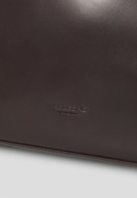 Mørkebrunt læder med et lille præget "VAGABOND SHOEMAKERS" logo centreret nær bunden.