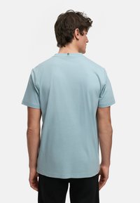 Lyseblå kortermet t-skjorte laget av myk bomull. Har rund hals og et lite logo-merke bak på nakken.