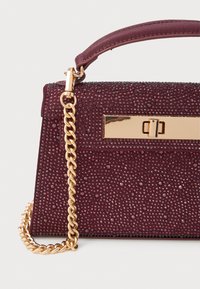 Geantă burgundy cu o suprafață texturată, decorată cu mărgele mici, având un lanț de aur și un detaliu cu închidere metalică rectangulară.