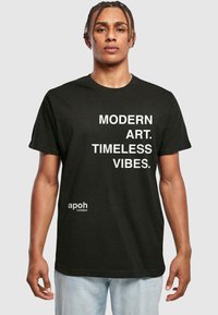Schwarzes Baumwoll-T-Shirt mit weißem Text: "MODERNE KUNST. ZEITLOSE VIBES." und kleinem "apoh London"-Logo auf der unteren linken Seite.