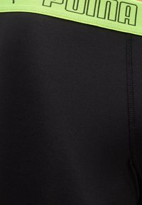 Μαύρα αθλητικά σορτς με ελαστική μέση σε νέον πράσινο χρώμα, διακοσμημένη με το λογότυπο Puma σε μαύρο με περίγραμμα, εμφανής ραφή στη πλευρά.