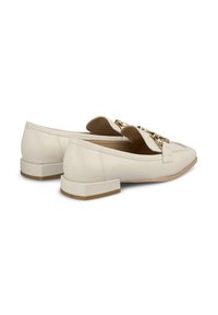 Mocassins en cuir beige à talon plat, avec un détail de chaîne dorée sur le devant et une texture lisse.