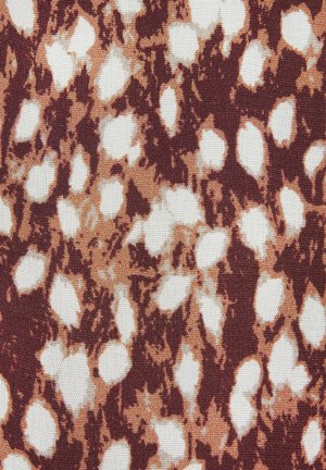Der Stoff zeigt ein Muster aus unregelmäßigen weißen und hellbraunen Formen auf einem dunkleren braunen Hintergrund, wobei eine strukturierte Webart sichtbar ist.