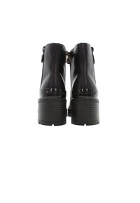 Svarta läderankleboots med en kraftig, ribbad klack och glansiga svarta detaljer. Har en dragkedja på sidan för enkel användning.