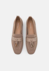 Mocasines beige con parte superior de punto, que cuentan con una tira de ante marrón y detalle de borlas. Punta redondeada y suelas planas para mayor comodidad.