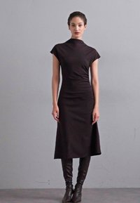 Rochie neagră, până la genunchi, cu guler înalt și mâneci scurte, realizată dintr-un material neted, având o siluetă ajustată.