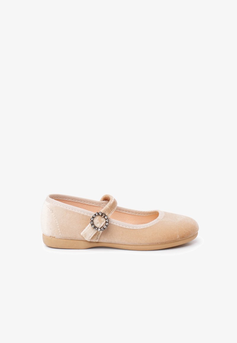 Scarpa piatta in velluto beige con punta tonda e una cintura con una fibbia di strass circolare su sfondo bianco.