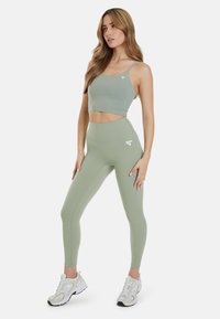 Lys grøn atletisk crop top parret med højtaljede leggings i samme farve. Fremstillet af strækbart stof med hvidt logo-detalje.