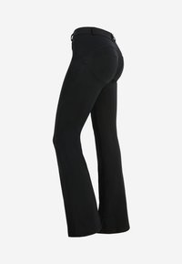 Musta flare-housut istuvalla muotoilulla, valmistettu venyvästä materiaalista. Ominaisuudeksi kuuluu klassinen vyötärö ja kaarevat takataskut yksityiskohtana.